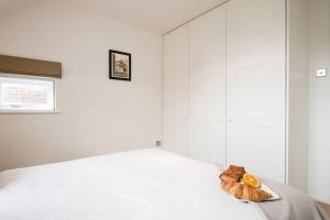 a bedroom with white walls and a bed with an orange on it at Modern Apartment in the Heart of Oxford with Secure Underground Parking in Oxford