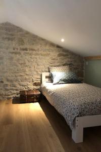 a bedroom with a bed and a stone wall at Gite avec mezzanine le Clos des Sœurs in Bainville-aux-Saules