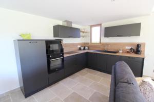 a kitchen with black cabinets and a stove top oven at Gite avec mezzanine le Clos des Sœurs in Bainville-aux-Saules