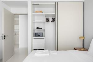 a white bedroom with a bed and a closet at Silkhaus Marina View with Tower's Private Beach in Dubai