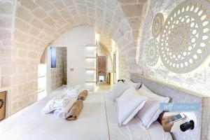 um quarto com uma cama branca e uma parede de pedra em Vico Bianco Raro Villas Smart Rooms Collection em Ostuni