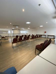 uma sala de conferências com cadeiras e um quadro branco num quarto em Transamerica Fit Vitória Reta da Penha em Vitória