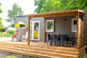 une maison avec une terrasse dotée d'une table et d'un parasol dans l'établissement Eurocamp Spreewaldtor, à Groß Leuthen