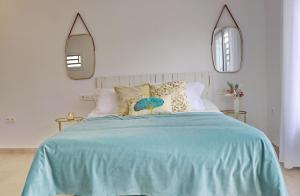 - une chambre avec un lit bleu et deux miroirs dans l'établissement La Ilusión, à Conil de la Frontera