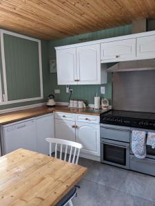 a kitchen with white cabinets and a table and a stove at Craigmile Cottage in Fraserburgh