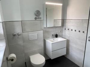 a white bathroom with a toilet and a sink at Strandhaus am Kurpark in Cuxhaven +100 photos