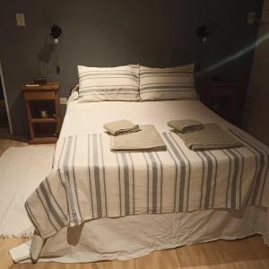 uma cama com um cobertor listrado e duas toalhas em los sauces em Suipacha
