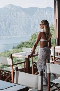 Eine Frau steht an einem Tisch und blickt auf die Berge. in der Unterkunft Hotel Querceto Wellness & Spa - Garda Lake Collection in Malcesine