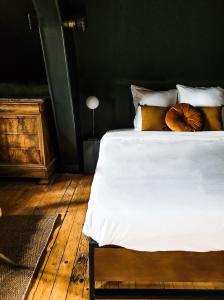 una camera da letto con letto, lenzuola e cuscini bianchi di Domaine Le Clos de la Source - Petit déjeuner buffet a Montrichard