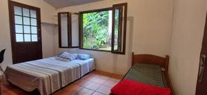 1 dormitorio con cama y ventana en Casa próxima à lagoa, en Florianópolis