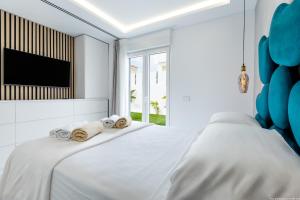 a white bedroom with a bed and a tv at VILLA NICOLE wifi, gym, Heated Pool in Callao Salvaje