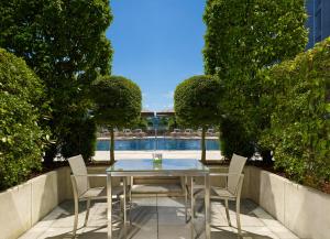 einen Tisch und Stühle mit Poolblick in der Unterkunft Hotel President Wilson, a Luxury Collection Hotel, Geneva in Genf