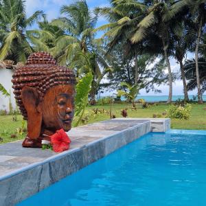una estatua sentada junto a una piscina en La Villa Boraha Location de villa entière en bord de plage Piscine privée Wifi Ile Sainte Marie, en Sainte Marie