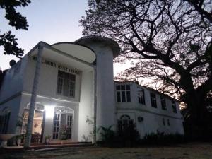 a large white building with a tree in front of it at Wellawaya Rest House in Wellawaya
