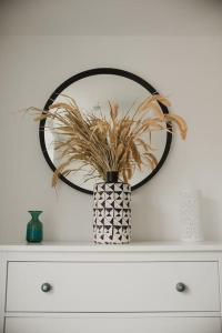 a mirror and a vase with a plant on a dresser at St Benedicts Street Flat with Roof Terrace in Norwich