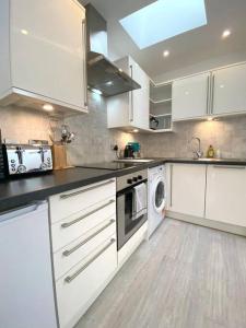 cocina con armarios blancos, lavadora y secadora en St Benedicts Street Flat with Roof Terrace, en Norwich