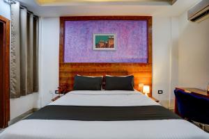 um quarto com uma cama com um quadro roxo por cima em luxury room on NH8 near Hero Honda Chowk Gurgaon em Gurgaon