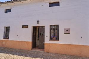 un edificio blanco con una puerta y dos ventanas en Zarzo del Tragaluz, en Fuenteheridos
