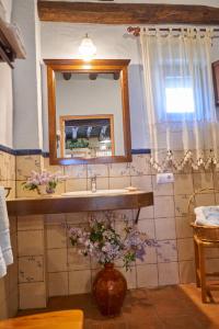 baño con lavabo, espejo y flores en Zarzo del Tragaluz, en Fuenteheridos