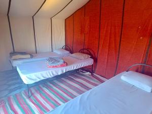 2 posti letto in una piccola camera con pareti rosse di Mhamid Sahara Camp - Mhamid El Ghizlane a M'Hamid