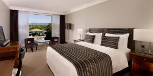 Schlafzimmer mit einem großen weißen Bett, einem Schreibtisch und einem Schreibtisch in der Unterkunft Hotel President Wilson, a Luxury Collection Hotel, Geneva in Genf