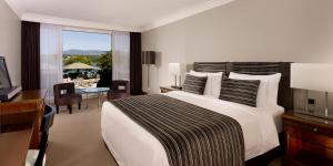 a bedroom with a large white bed with a desk and a desk at Hotel President Wilson, a Luxury Collection Hotel, Geneva in Geneva