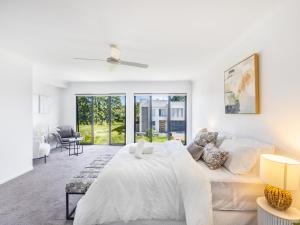 - une chambre blanche avec un lit et un canapé dans l'établissement 2024 Brand-new 5BR Comfort House in SunnybankHills, à Brisbane