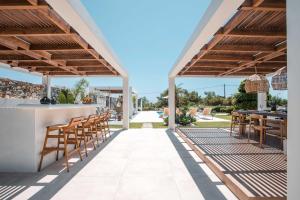eine Terrasse mit einer Bar mit Stühlen und Tischen in der Unterkunft Oneiro Villa - Voted the best Villa in Rhodes, Greece! in Pefki Rhodes