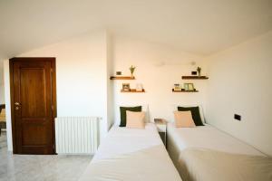 2 bedden in een witte kamer met een deur bij The Librarian's home in San Gimignano