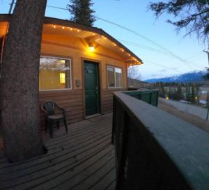 a house with a chair on a porch with a tree at Alpenrose , hottub, Big Deck, Mountain Views in Golden