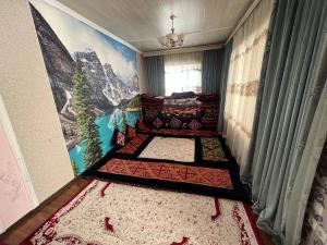ein Zimmer mit mehreren Teppichen auf dem Boden mit einem Gemälde in der Unterkunft Green West House in Bischkek