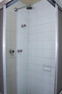 eine Dusche mit weiß gefliesten Wänden und einer Glastür in der Unterkunft Plaza Prestige Hotel Manaus in Manaus