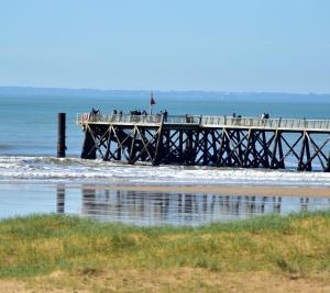 - une jetée avec des gens debout dans l'océan dans l'établissement Studio Bords de plage, à Saint-Jean-de-Monts