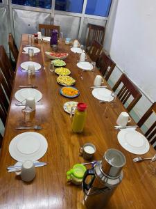 una larga mesa de madera con platos de comida. en Sanaa Hostel en Zanzíbar