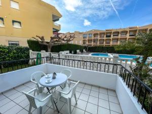 einen Balkon mit einem Tisch, Stühlen und einem Pool in der Unterkunft Apartamentos Entreplayas 3000 in Oropesa del Mar