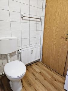 ein Badezimmer mit Toilette und Holztür in der Unterkunft Lehn dich zurück in Mühlhausen