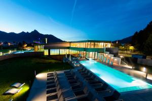 a large building with a swimming pool at night at Hotel Krone Tirol in Reutte