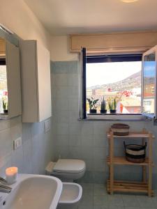 uma casa de banho com um lavatório, um WC e uma janela. em La Mansarda em Como