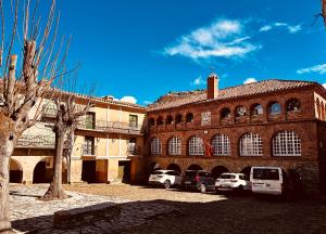 a large brick building with cars parked in front of it at Albergue Rural de Yanguas in Yanguas