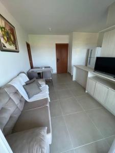 a living room with white furniture and a kitchen at Vista Mar Buraquinho in Lauro de Freitas
