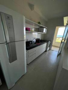 a kitchen with a white refrigerator and a white tile floor at Vista Mar Buraquinho in Lauro de Freitas