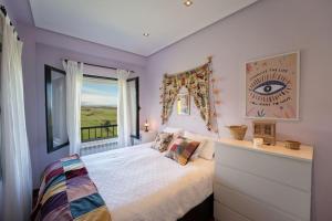 a bedroom with purple walls and a bed with a window at casa saida in Liencres