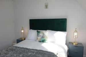 a bedroom with a bed with a green headboard and two lamps at Tulip Place in Chelmsford