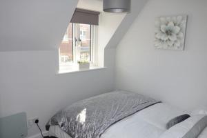 a white bedroom with a bed and a window at Tulip Place in Chelmsford