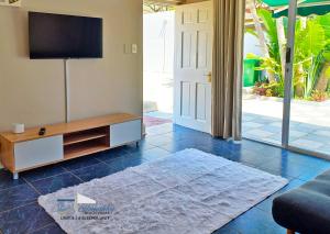 a living room with a flat screen tv and a couch at Glen Ashley Beach Villas in Durban