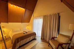 フェルナンド・デ・ノローニャにあるCabana Gameleira - Viagem Inspiradaのベッドルーム1室(ベッド1台、椅子、窓付)