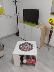 un soggiorno con tavolo bianco e TV di Apartman Plaza 9 a Veliko Gradište