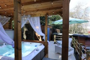 una terraza con bañera de hidromasaje y sombrilla en Le Chic Retreat - Luxury Hot Tub Getaway, en Bournemouth