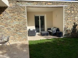 a patio with two chairs and a stone wall at Casa Laura in Cervione