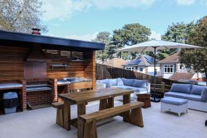 un patio con una mesa de madera y una parrilla en Le Chic Retreat - Luxury Hot Tub Getaway, en Bournemouth